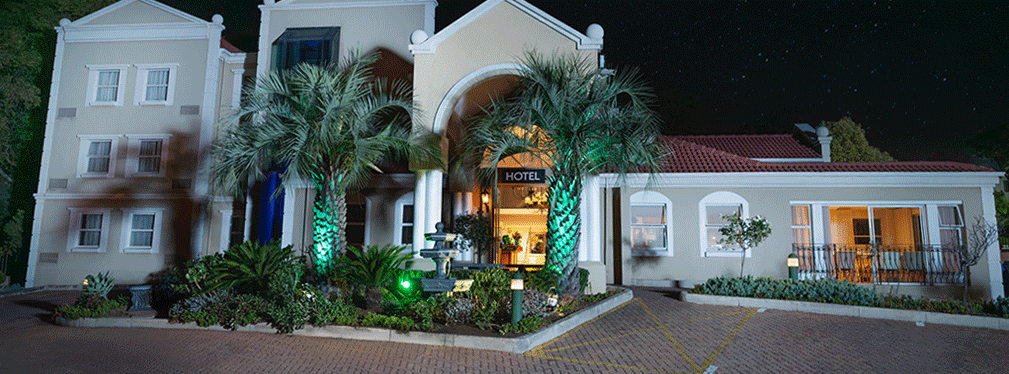 Illuminated hotel entrance with palm trees at night
