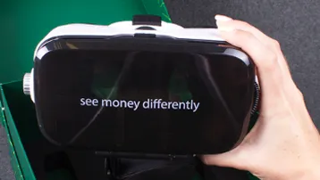 Hand holding VR headset displaying money message