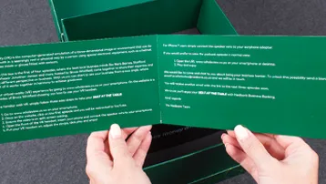 Hands holding green folded leaflet beside matching box